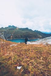 Back view of a man in dark outfit standing by lake shore in Italy