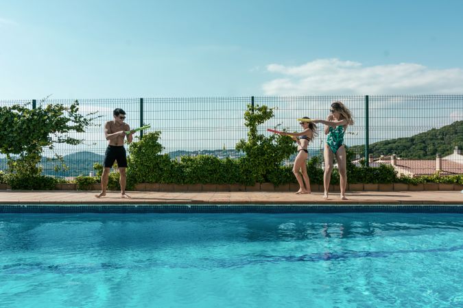 Friends playing with water pistols in the pool