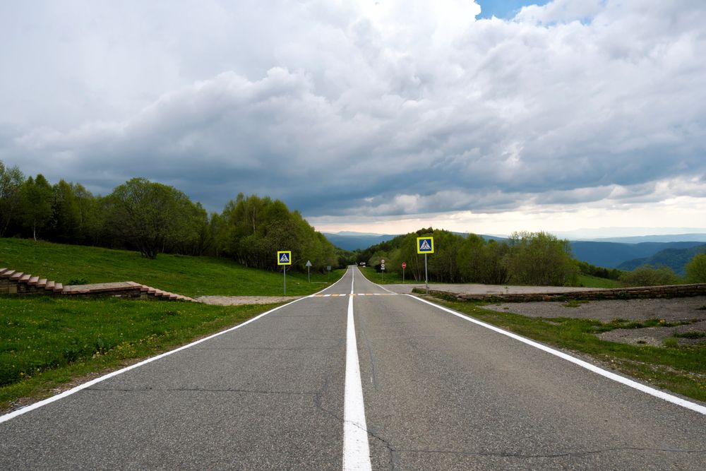 Straight road leading into distance with cloudy sky.