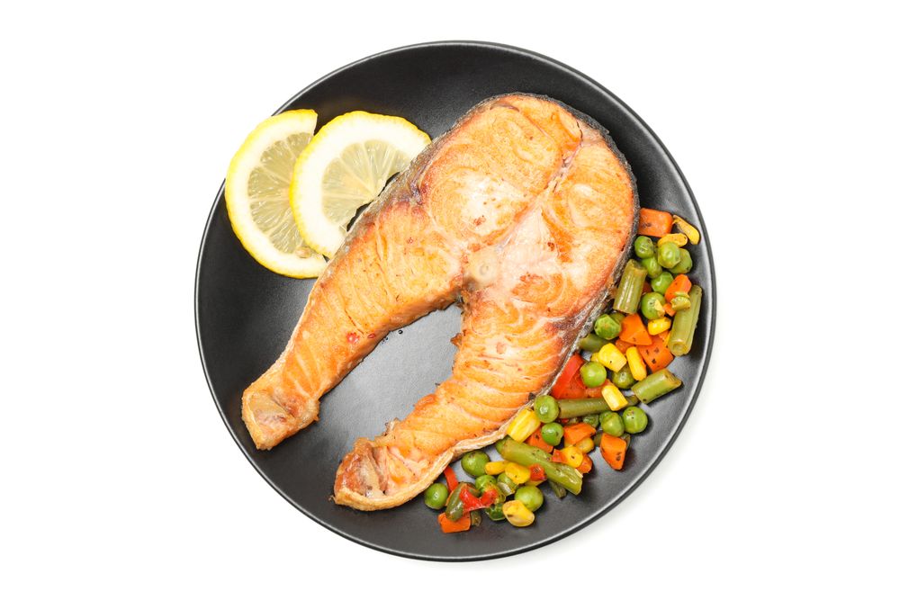 Plate with grilled salmon and vegetables isolated on blank background