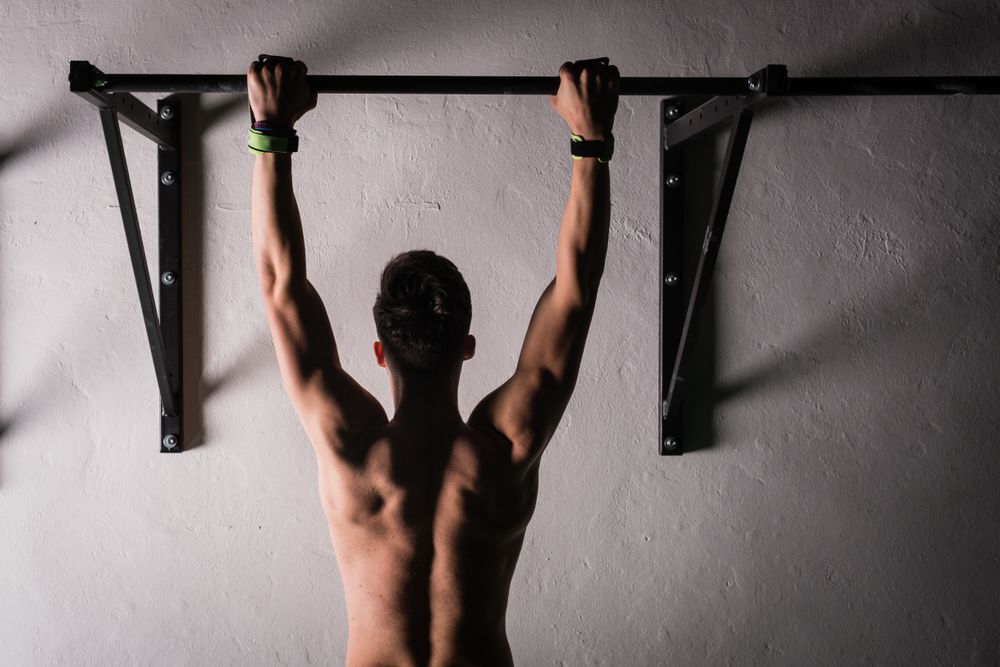 Man hanging on bar near wall in gym