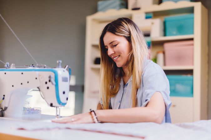 Cheerful seamstress using sewing machine