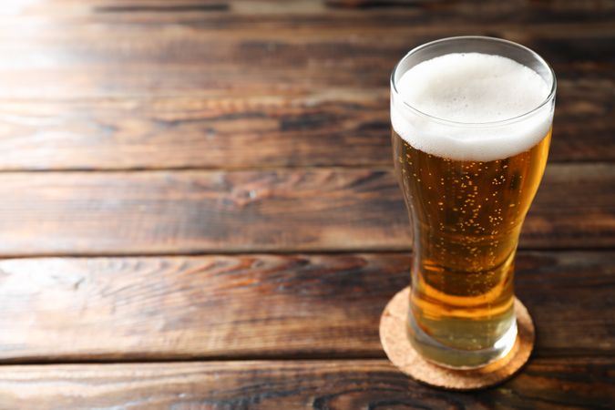 Mug with beer on wooden table, space for text