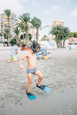 Boy in snorkeling mask and flippers on beach