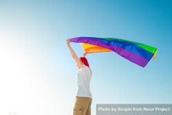 Woman holding rainbow flag under blue sky 5zpPAb