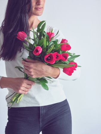 Crop woman embracing beautiful fresh bouquet of tulips