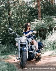 Woman sitting on cruiser motorcycle parked on dirt road 4A8XN5