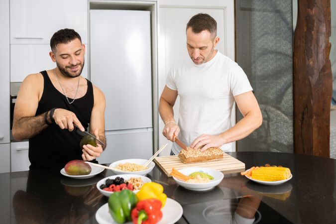 Male couple preparing vegetables and bread for lunch
