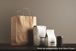 Two bags of coffee beans with brown paper bag and to-go cup bYWxd5