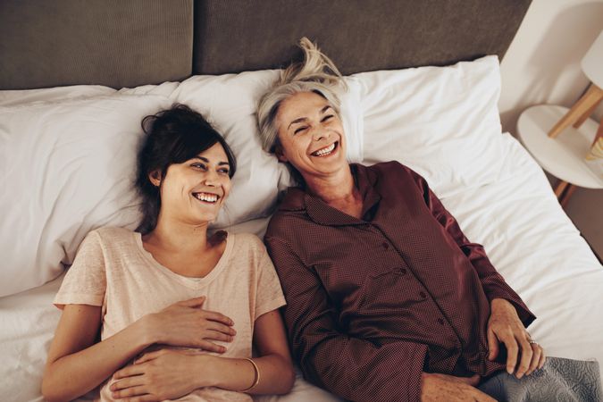 Woman spending time talking with her mother lying on bed at home