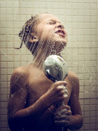 Content boy taking shower in bathroom
