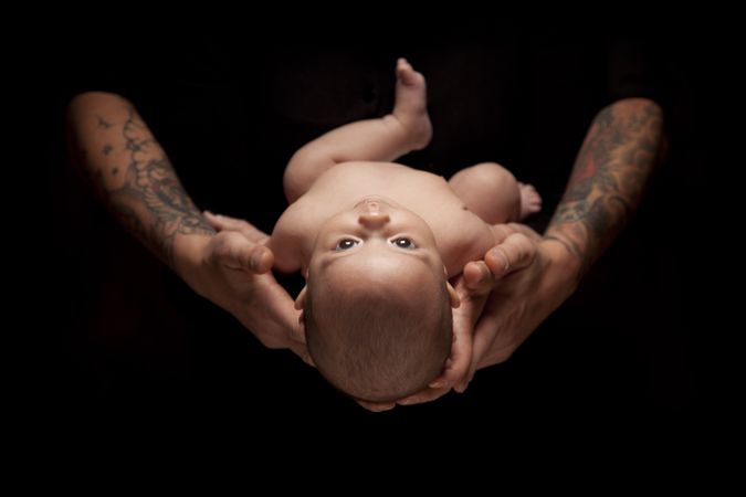 Hands of Father and Mother Hold Newborn Baby