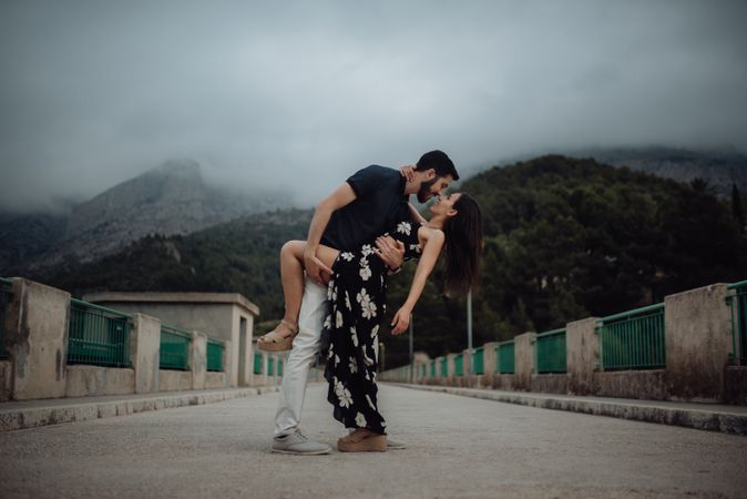 Sensual couple embracing while on rural bridge