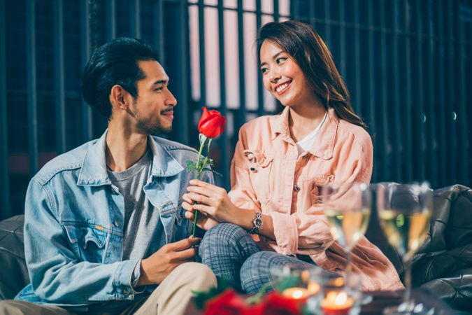 Asian man giving rose to his girlfriend on date night