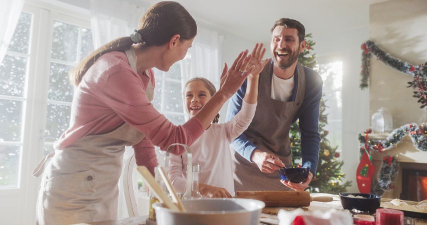 Happy Family During Christmas: Portrait of Little Cute Girl Learning How to Make Cookies and Celebrating her Achievement with her Parents.