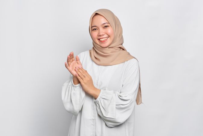Asian female in headscarf clapping her hands and smiling