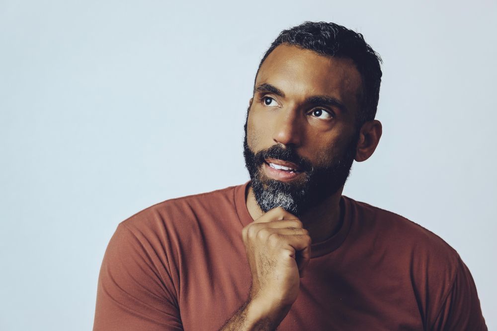Head shot of thinking Black male looking up in grey studio