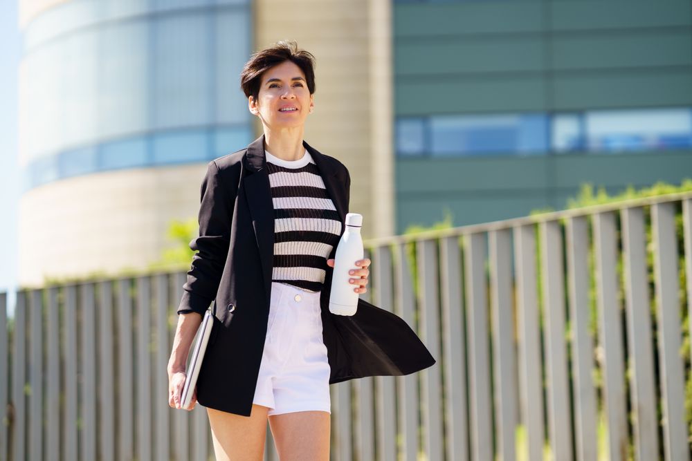 Woman walking outside with computer and water bottle