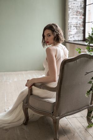 Gorgeous woman with red lips in white dress sitting on armchair
