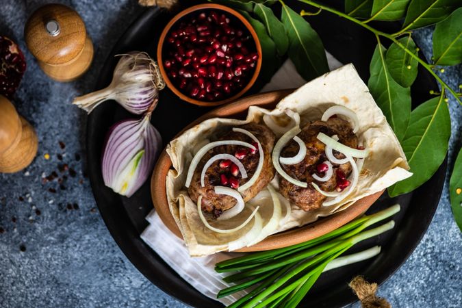 Top view of Georgian dish of abkhazura meat cutlets on plate with pomegranate seeds and bay leaves