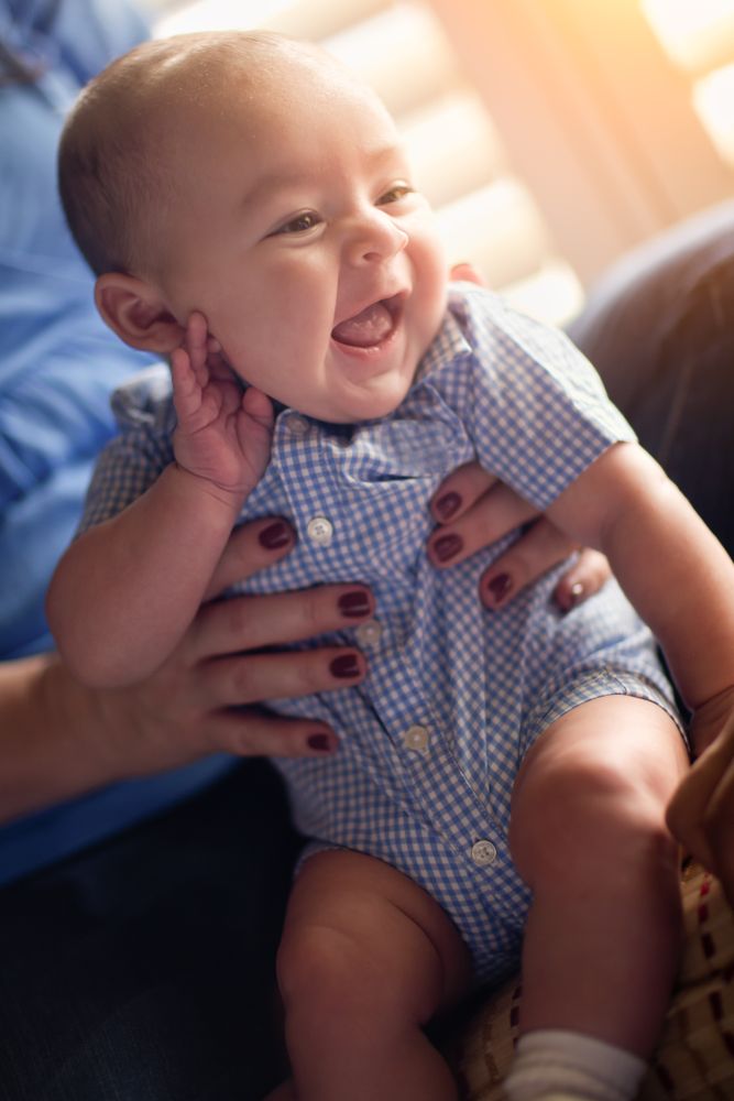 Happy Couple Enjoying Their Newborn Son In The Light of The Window.
