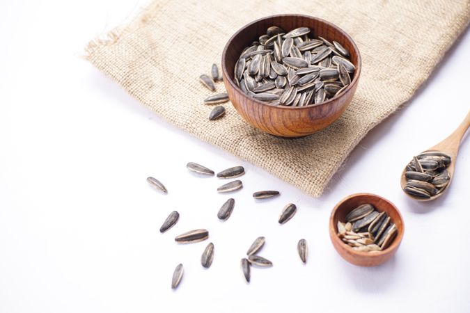 Sunflower seeds in wooden bowl and wooden spoon on table with brown cloth