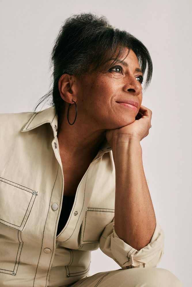 Woman in stylish jumpsuit with hand under chin looking contemplatively