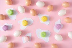 Brown eggs and pastel macarons on pink background