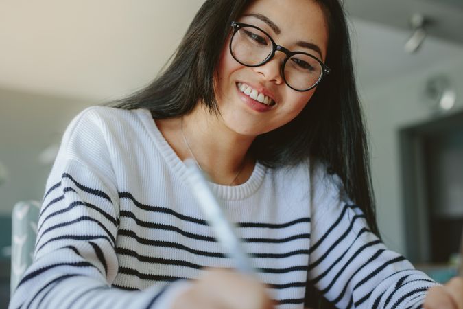 Smiling young woman wearing eyeglasses studying at home