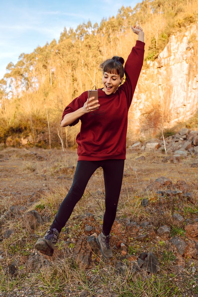 Young woman with smartphone dancing
