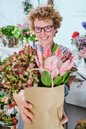Smiling woman with bouquet of various flowers in shop
