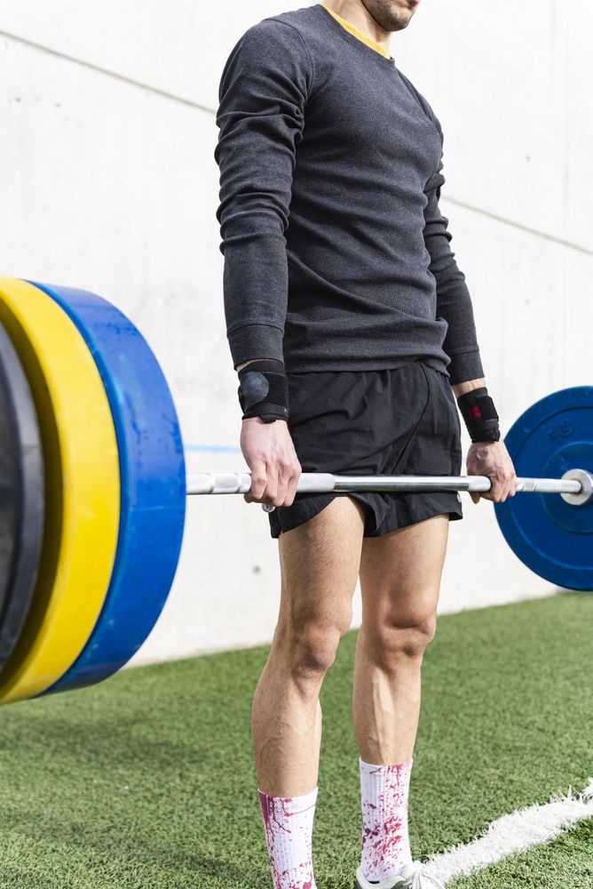 Man training with barbell on sports ground