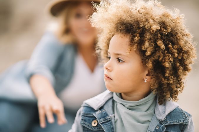 Focused curly child resting with mother