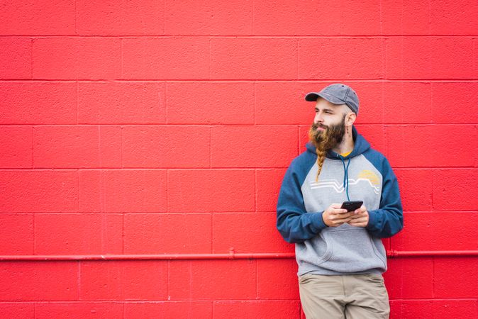 Man using smartphone near red wall
