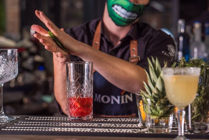 Bartender adding mint leaves to an alcoholic mix