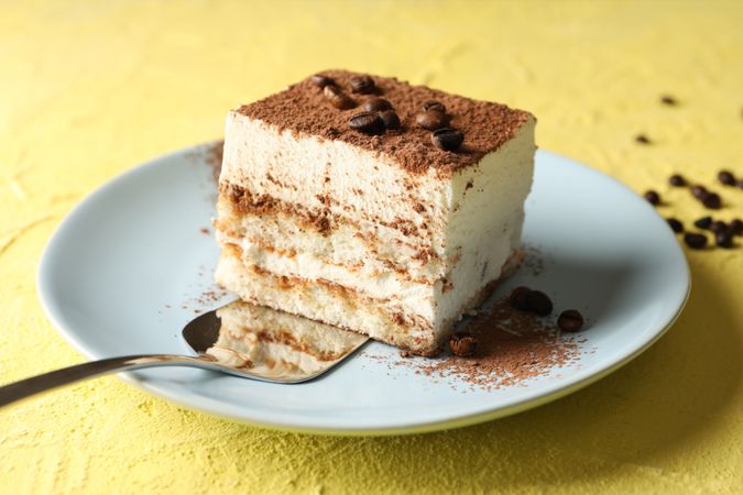 Plate with delicious tiramisu on yellow background. Tasty dessert