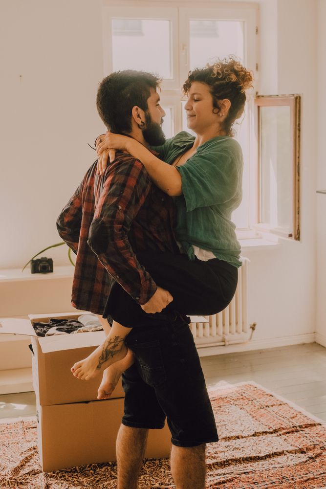 Happy couple embracing in room next to cardboard boxes
