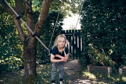 Blonde girl with braided hair leaning on outdoor swing