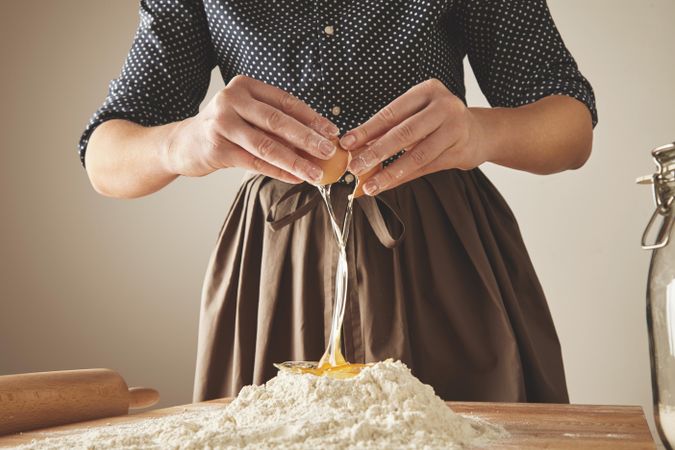 Woman cracking an egg into a pile of flour
