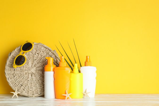 Summer vacation accessories on white table against color background, space for text. Safe tan