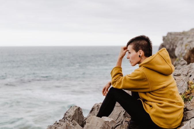 Woman in yellow hoodie on stony shore
