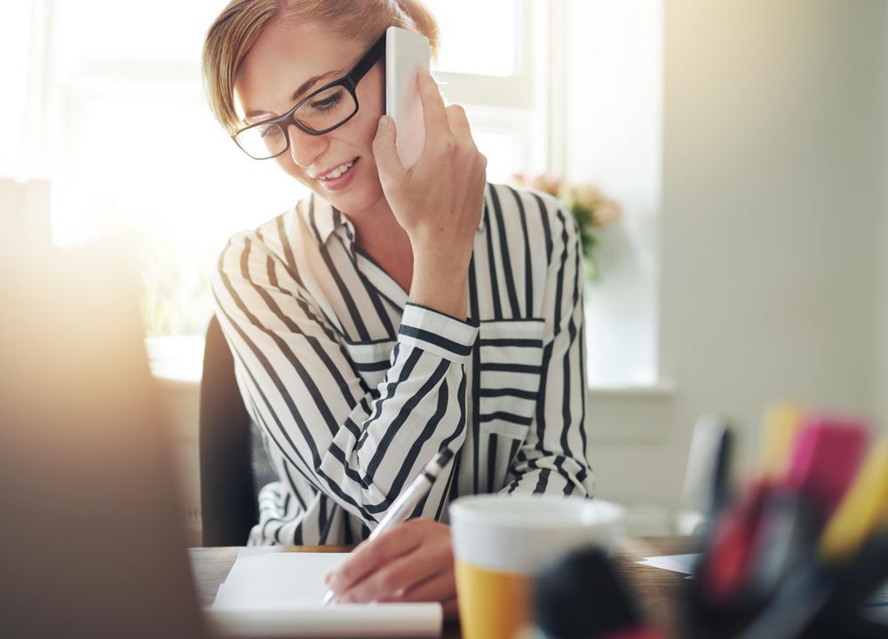 Woman in striped shirt taking phone call at her desk