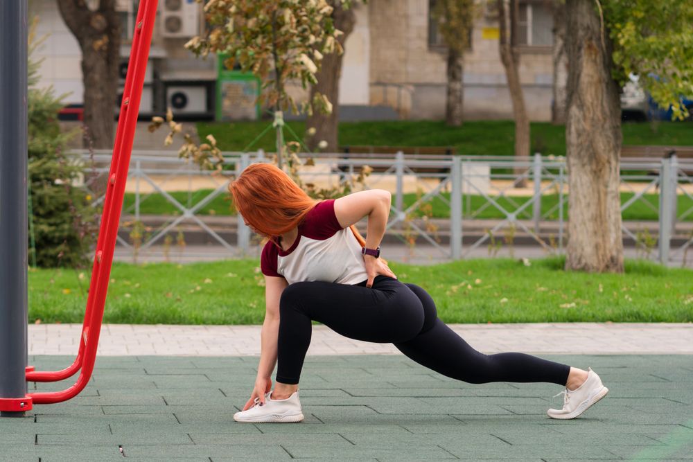 Woman in deep lunge stretch, hand touching foot