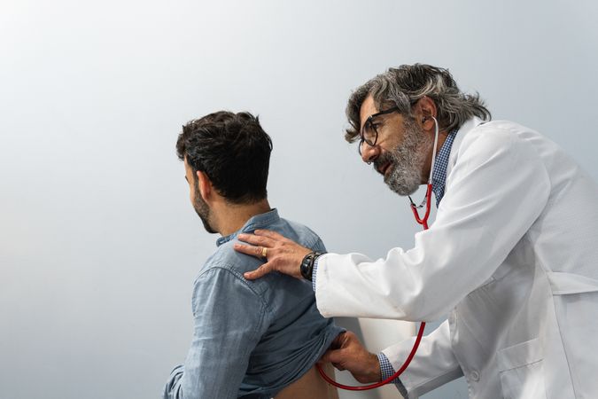 Male doctor using stethoscope and examining patient
