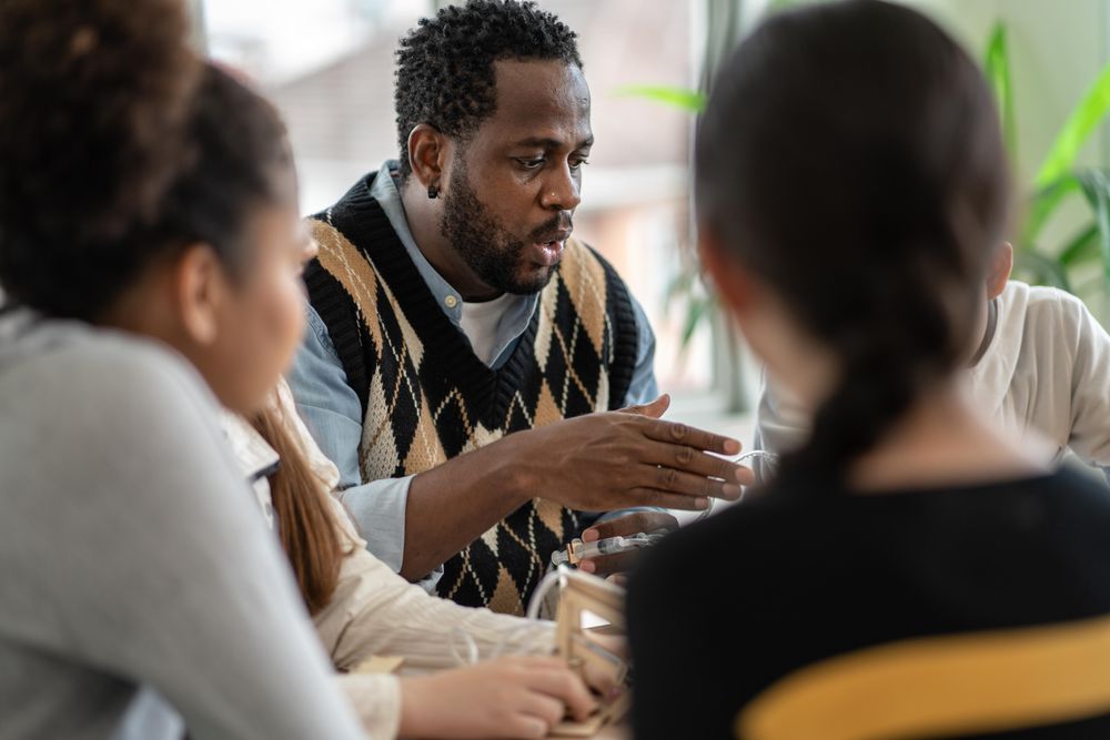 Male teacher leading science lessons around a table of teenage students