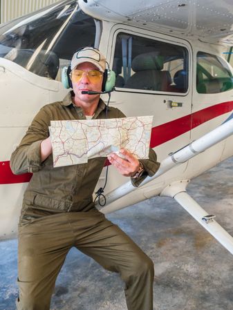 Pilot with map beside small plane