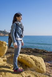 Woman standing tall looking out to the ocean on clear day, vertical