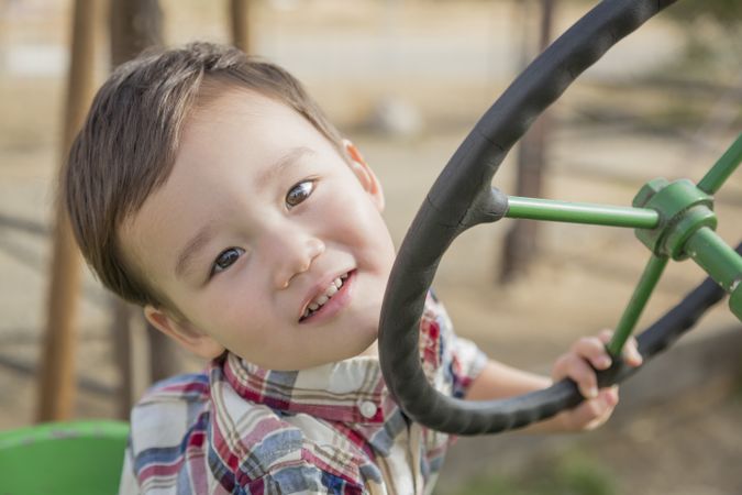 Biracial Boy Playing on Tractor In Field