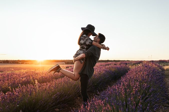 Beautiful romantic photo of a couple in a field of flowers at sunset