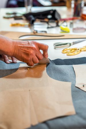 Fashion designer outlining fashion patterns with a tailor's chalk. Vertical shot.